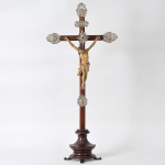 <b>Crucifixo </b>em jacarandá com figura de Cristo entalhada e patinada, com o seu perizônio apresentando realce em dourado. Resplendor com pedra ao centro. Ponteiras e símbolos sacros em prata. Séc. XIX. Alt. 92 cm