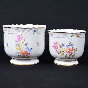 <B>Conjunto de duas jardineiras</B> em porcelana húngara, decoradas em policromia de flores e frisos levemente torcidos. Bordas filetadas a ouro. Marca da manufatura e numeração no verso. Primeira metade do séc. XIX. Alt. da maior 16 cm; Diâm. da maior 19 cm