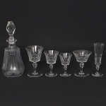 MAISON BACCARAT - <B>Serviço de copos </B>em cristal com bojos lapidados em sulcos e geometrizados. Base circular. Timbre da "cristallerie" na base. Constando de 14 copos p/ água, 12 flutes, 12 taças de champanhe, 14 copos p/ vinho tinto, 11 copos p/ vinho branco e 1 licoreiro. Total de 64 peças.