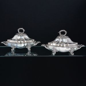 <b>Par de "entrée dishes"com tampa </b>em prata inglesa vitoriana, decorada em gomos com pegas em rebuscada decoração de elementos vegetais. Parte inferior refere ao "réchaud" em metal espessurado a prata seguindo o mesmo padrão decorativo. A tampa com contraste e marca do prateiro JCE. Compr. 40,5 cm