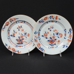 <b>Par de pratos </b>circulares em porcelana Companhia das Índias decorada com ramagens e flores em policromia "Chinese Imari" (um deles com imperceptíveis bicadinhos na borda). Séc. XVIII. Diâm. 23 cm