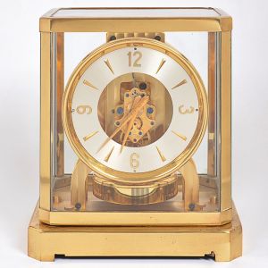 <b>JAEGER LECOULTRE ATMOS </b>- Numeração 10612. Relógio de mesa com redoma em vidro e montagem em bronze dourado. Med. 23,5 x 21 x 16 cm