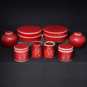 Decorativo <b>lote de peças em porcelana chinesa</b>, cobertos por esmalte dito "sangue de boi". Constando de par de caixas circulares (diâm. 22,5 cm), par de porta pincéis cilíndricos (alt. 11,5 cm), par de potes cilíndricos com tampa (alt. 10,5 cm; diâm. 11,5 cm) e par de potiches "ginger jars" bojudos (alt. 14 cm).