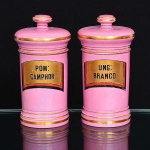 <b>Par de potes de farmácia</b> franceses em porcelana na cor rosa com rótulos de designação com frisos em negro e vermelho fogo sobre fundo dourado. Filetados a ouro. Séc. XIX. Alt. 29,5 cm