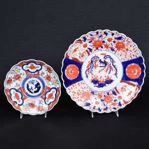 <b>Conjunto de travessa e covilhete </b>circulares em porcelana japonesa, decorados em policromia florida no padrão "Imari". Bordas onduladas. Séc. XIX. O menor com restauro de 1,5 cm na borda. Diâm. 31 e 21,5 cm