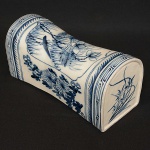 <b>Travesseiro</b> chinês em porcelana, decorado em azul índigo "underglaze" com composições floridas sobre fundo branco. Séc. XIX. Alt. 17 cm; Compr. 35,5 cm