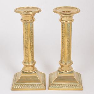 <b>Par de castiçais </b>europeus em bronze dourado lavrado com elementos vegetais. Coluna cilíndrica e base quadrada. Alt. 19,5 cm