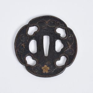 <b>Tsuba</b> japonesa em ferro forjado estilo Heianjo, de formato quadrilobado "Mokko". Apresenta nos dois lados adornos vazados "Inome" e relevos com embutidos em metal amarelo "Takazogan", com flores, volutas e bordas em torsades. Séc. XVII. Diâm. 8 cm