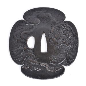 <b>Tsuba</b> japonesa, de excepcional tamanho, em ferro forjado, de formato quadrilobado "Mokko", lavrada em relevo. Frente apresentando tradicional motivo "Taketora-zu", com tigre e bambus. Verso com nuvens e chuva sobre riacho com pedras ao fundo. Período Edo (1603-1867). Diâm. 10,5 cm