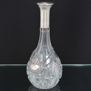 <b>Garrafa </b>piriforme em cristal francês provavelmente BACCARAT, apresentando lapidação geometrizada. Gargalo em prata europeia com contraste ilegível e marca de prateiro. Acompanha colar em prata 833. Alt. 30 cm