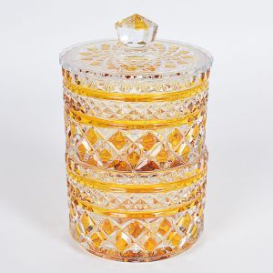 "<b>Bonbonnière</b>" cilíndrica em "demi" cristal com compartimentos circulares sobrepostos sendo o superior com tampa. Lapidação em losangos de tonalidade laranja. Alt. 21 cm