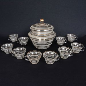 <b>Poncheira </b>em vidro com tampa e 10 canecas de provável origem norte-americana decorada em jateado e filetes a ouro. Década de 30 / 40. Uma caneca com ínfimo bicadinha na borda. Alt. 28,5 cm; Diâm. 28,5 cm