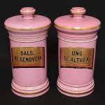 <b>Par de potes de farmácia </b>em porcelana francesa de Limoges, do séc. XIX, na cor rosa. Apresentam a designação dos produtos (UNG: DE ALTHEA e BALS: DE GENOVEVA) em rótulos a ouro com filetados em "rouge de fer" e negro. Alt. 30 cm