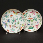 <b>Par de pequenos pratos </b>circulares em porcelana chinesa decorada em policromia com borboletas, flores e folhas. Séc. XIX. Diâm. 17,5 cm