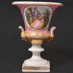 <b>Vaso</b> em porcelana francesa Império, na cor rosa, com interior e base brancos. Decoração com reserva de cena romântica em policromia. Alças implantadas em carranca e realces a ouro. Alt. 21,5 cm