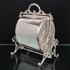 <b>Biscoiteira ou porta torradas</b> inglês em metal espessurado a prata apresentando dois compartimentos articulados com interior trabalhado em vazados. Decoração externa com ramos. Alt. 26 cm; Compr. 22 cm