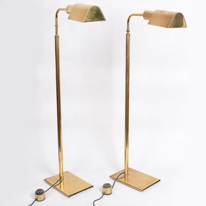 <b>Par de luminárias</b> de altura regulável, em metal dourado, com bases retangulares, hastes cilíndricas e cúpulas pivotantes. Metal com algum desgaste na base. Alt. 95 cm