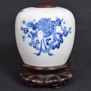 Pequeno <b>potiche </b>em porcelana chinesa de forma globular decorada com flores e símbolos em azul índigo "underglaze" sobre fundo branco. Pequeno orifício circular na parte superior com mínima lasquinha. Pequena tampa em madeira. Acompanha base em madeira. Alt. sem a base 11 cm