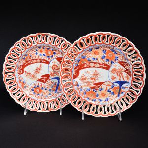 <b>Par de pratos </b>circulares em porcelana "Imari", decorado com flores e estilizações características em "rouge de fer" e azul índigo "underglaze". Borda vazada em círculos entrelaçados. Séc. XIX. Diâm. 21 cm