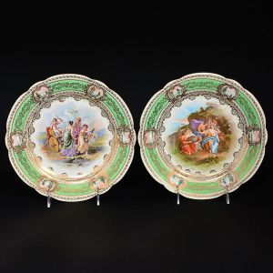 ANGELICA KAUFFMANN  <b>Par de pratos </b>de coleção ditos"cabinet plates" em porcelana de Viena, decorados em bela policromia com cenas românticas. Borda com larga faixa verde pistache decorada com guirlandas a ouro intercaladas por cartucho com paisagens. Um deles com assinatura da artista. Séc. XIX. Diâm. 24,5 cm