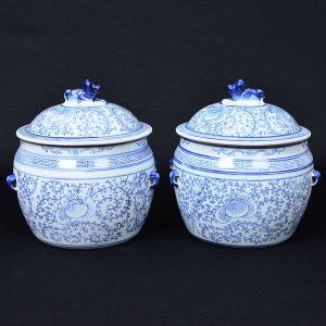 <b>Par de potiches </b>bojudos chineses em porcelana, profusamente decorados com arabescos floridos em azul índigo "underglaze". Tampas encimadas por cães de fó. Alt. 22,5 cm