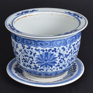 "<b>Cachepot</b>" com seu prato, de forma circular, em porcelana chinesa, apresentando decoração com flores e arabescos em azul índigo sobre fundo branco. Alt. 15 cm; Diâm. do "cachepot" 21 cm