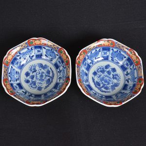 <b>Par de pequenos "bowls" </b>em porcelana japonesa azul e branco, com bordas recortadas decoradas com arabescos floridos predominando tonalidades de "rouge de fer", azul e verde com realces a ouro. Alt. 4,5 cm; Diâm. 14,5 cm