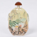 Rara e grande "<b>snuff bottle</b>" chinesa, de mesa, de formato retangular ovalado, em vidro transparente, moldada e ladeada por pegas laterais com máscaras de leão e argolas. Parte interna inteiramente ornamentada por fina e delicada pintura com paisagens, montanhas, rios, barcos, edificações e figuras. Acompanha poema assinado no topo. Base anelada oval. Tampa sem colher para evitar danos à pintura. Alt. 14,5 cm