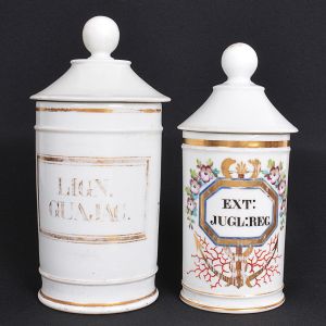 <b>Conjunto de 2 potes de farmácia </b>em porcelana francesa. Um com decoração com rótulo e frisos a ouro sobre fundo branco e outro com decoração com rótulo em policromia e ouro. O maior com imperceptível bicado interior da tampa. Alt. 27 cm e 24 cm