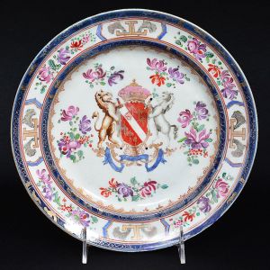 <b>Prato raso</b> circular em porcelana francesa Sanson, decorado ao gosto dos originais da Companhia das Índias feitos para o mercado europeu. Centro com grande brasão armorial cercado por ramos de flores em policromia, que se repetem na borda. Apresenta dois filetes em azul cobalto realçados a ouro. Marca no verso. Séc. XIX. Diâm. 23,5 cm