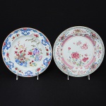 <b>Conjunto de dois pratos rasos</b> circulares, em porcelana Companhia das Índias, apresentando decorações distintas, em policromia florida, sendo um predominando tonalidade de rosa e o outro, tonalidade de azul. Séc. XVIII. Um deles com mínimo bicado no verso. Diâm. de ambos 22,5 cm