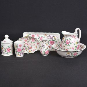 <b>Conjunto para "toilette" </b>em faiança inglesa decorada em policromia com ramagens de flores e pássaros sobre fundo creme. Marca da manufatura no verso. Constando de jarra com bacia, pote com tampa, pequeno vaso piriforme, copo, saboneteira e travessa retangular para escovas. Saboneteira com fio de cabelo. Total de 6 peças. Compr. da travessa 31 cm