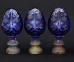 <b>Conjunto de 3 pinhas</b> francesas em cristal translúcido com "overlay" em azul cobalto, lapidadas com trevos e círculos. Bases em bronze. Apresentam rachadinhos e pequenos lascados nos pescoços. Séc. XIX. Alt. 19,5 cm