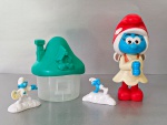 Lote com 3  Smurfs e 1 casa de Smurf. Altura do Smurf maior: 14.5 cm, Altura do Smurf menor: 4 cm, Altura da casinha: 11 cm, Peso total: 130 gr.