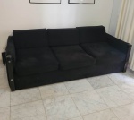 SÉRGIO RODRIGUES - Sofá de três lugares modelo "Millôr" executado em jacarandá maciço com corpo estofado em tecido, inclusive nas laterais. Assentos e encostos em almofadas soltas revestidas em tecido preto e acabamentos com botões em metal cromado. Brasil, c. 1965. Medidas: 199 cm x 97 cm. Altura: 67 cm. RETIRADA NA LAGOA (RJ) COM AGENDAMENTO.