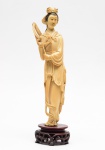 Estatueta de marfim representando gueixa apoiada sobre base de madeira. Altura total: 35 cm.