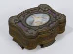 Caixa porta jóias em bronze francês com adornos em esmalte no tampo na cor lilás (pequeno restauro no esmalte). Interior almofadado forrado em tecido (gasto pelo tempo). Apresenta na parte central do tampo pintura sobre placa de marfim. Medidas: 15 cm x 12 cm. Altura: 8 cm.