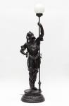 Escultura luminária em petit bronze representando figura de soldado. Altura total: 127 cm.