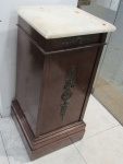 Mesinha auxiliar com uma gavetinha na parte frontal. Possui uma portinha na parte posterior com espaço interno separado por prateleira e parte interna inferior revestida por mármore branco. Possui tampo em mármore branco (com marcas de ferrugem). Medidas: 32 cm x 32 cm. Altura: 77 cm.