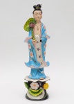 Estatueta de louça chinesa representando figura de gueixa. Falta a mão esquerda. Altura: 46 cm.