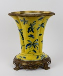 Vaso ovalado em faiança europeia UW (United Wilson) com base e acabamento em bronze, na tonalidade amarela com trabalho de flores e insetos na cor azul. Medidas 28cm x 25cm x 3 3cm de altura.