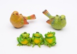 Itens de resina, sendo: A) dois pássaros medindo: 13 cm x 9 cm altura; B) três sapinhos, medidas: 18 cm x 7 cm altura.