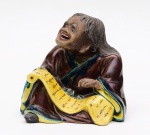 Escultura em faiança possivelmente oriental representando figura de ancião. Medidas: 15 cm x 12 cm. Altura: 12 cm.