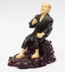 Escultura oriental representando ancião em bronze e marfim sobre base de madeira. Medida da base: 16 cm x 11 cm. Altura: 18 cm.