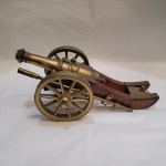 Canhão miniatura em metal dourado e madeira. Medidas: 24 cm x 11 cm. Altura: 10 cm.