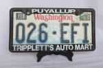 ITENS AUTOMOBILÍSTICOS - ANTIGA placa de Automóvel dos Estados Unidos da América, Estado de WASHINGTON (número 026.EFI), acoplada em uma Moldura plástica de revendedor (PUYALLUP TRIPPLETT`S AUTO MART). Com a moldura mede aproximadamente 31cm de comprimento. 