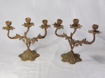 Par de candelabros para três velas em bronze, hastes e bobeches no feitio de folhagens, base decorada com flores e volutas. Alt. 26cm.