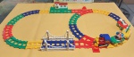 Lindo e divertido Trem Alegre Musical - FUNNY TRAIN SET - Som Eletrônico - Locomotiva e vagões acoplados por imã - 2 pistas com desvios -  Funcionamento com 2 pilhas AA na Locomotiva e 2 pilhas AA na Estação. Funcionando perfeitamente. Acondicionado na caixa original, porém com restauro de durex. OBS: Em 2 vagões estão faltando os bonequinhos, conforme fotos. Medida da caixa: 48 cm x 33 cm x 9 cm. Medida da locomotiva: 11 cm x 8 cm x 10 cm de altura. Medida aproximada da pista montada: 115 cm de comp x 60 cm larg.