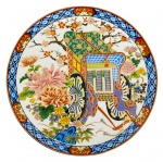 JAPÃO - Gracioso medalhão em porcelana japonesa fartamente adornada com carruagem e flores em policromia e vibrante. Mede 20,5cm diâmetro.