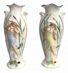 ART NOUVEAU - Par de graciosas floreiras em porcelana esmaltada adornadas com figuras humanas e folhagens ao estilo ART NOUVEAU. Possui sinal de restauro. No estado. Mede 18cm altura cada.